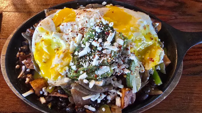 Cast iron skillet with eggs, avocado, black beans and cotija